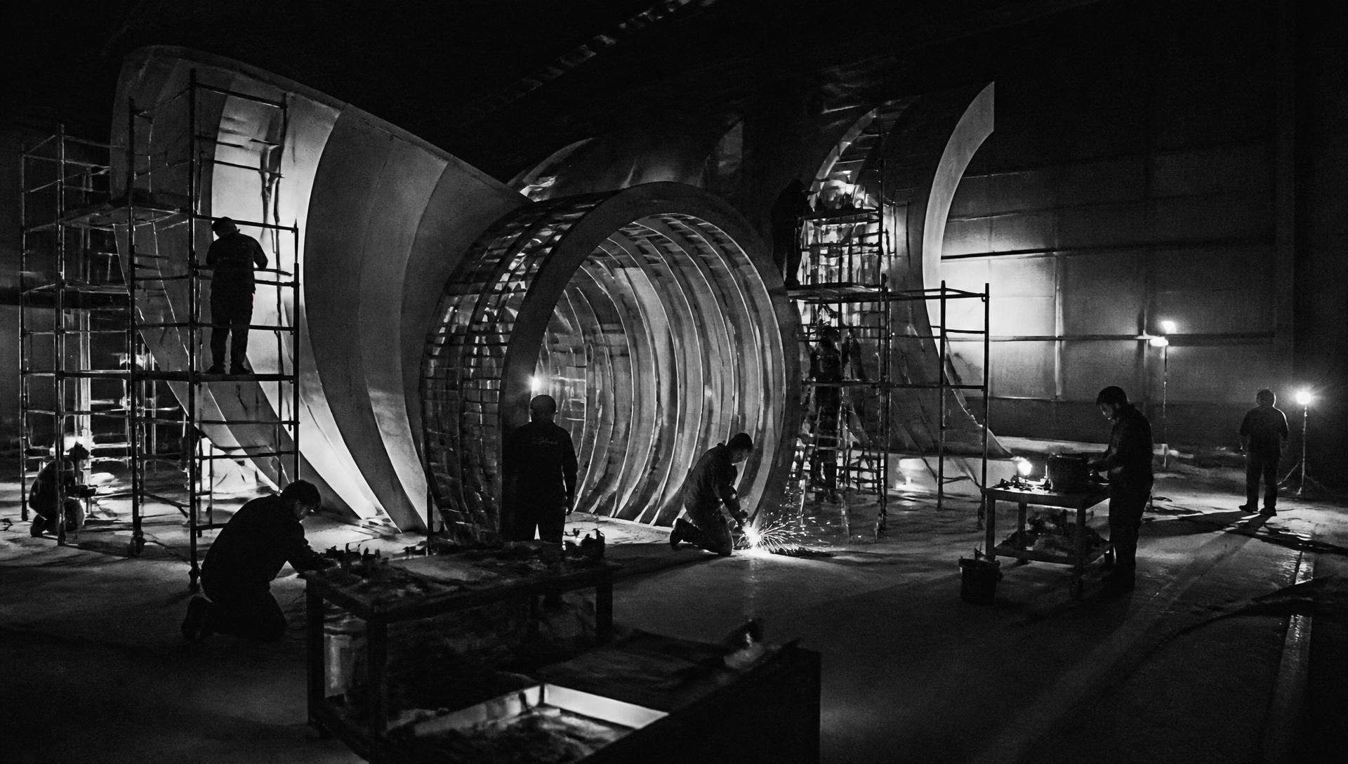 Production crew building a large-scale experience set at night