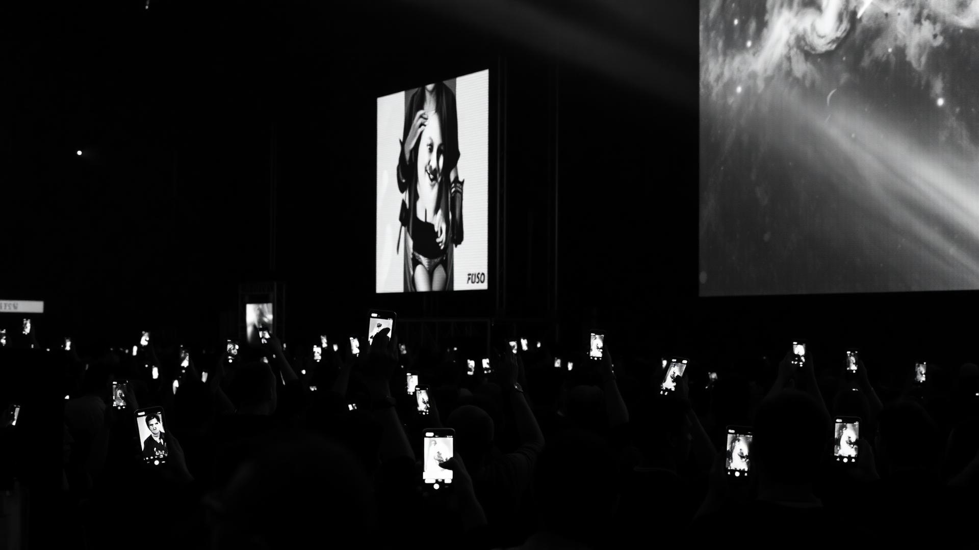 Crowd interacting with a giant screen using their phones at a live event