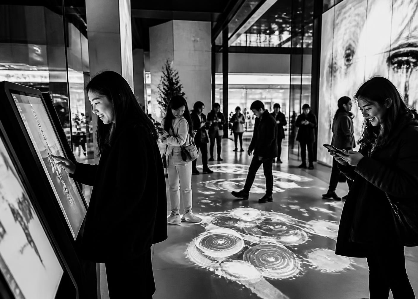Visitors using interactive screens and a projected floor experience in a retail atrium